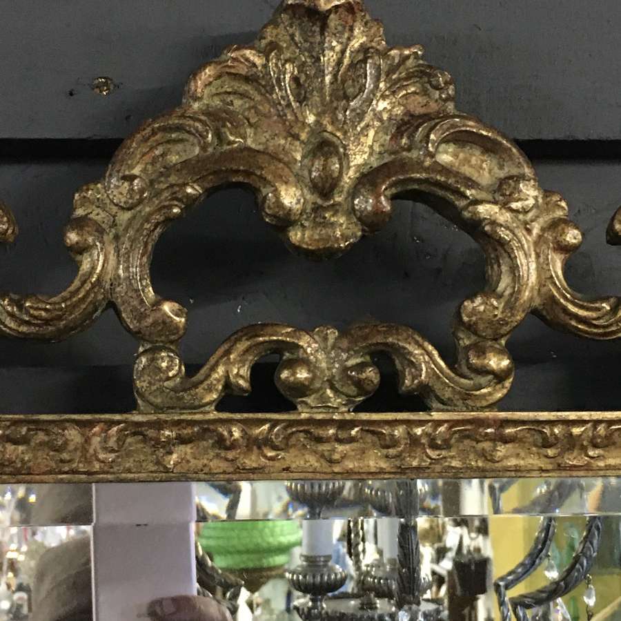 Bevelled glass mirror in an ornate gilded and aged frame